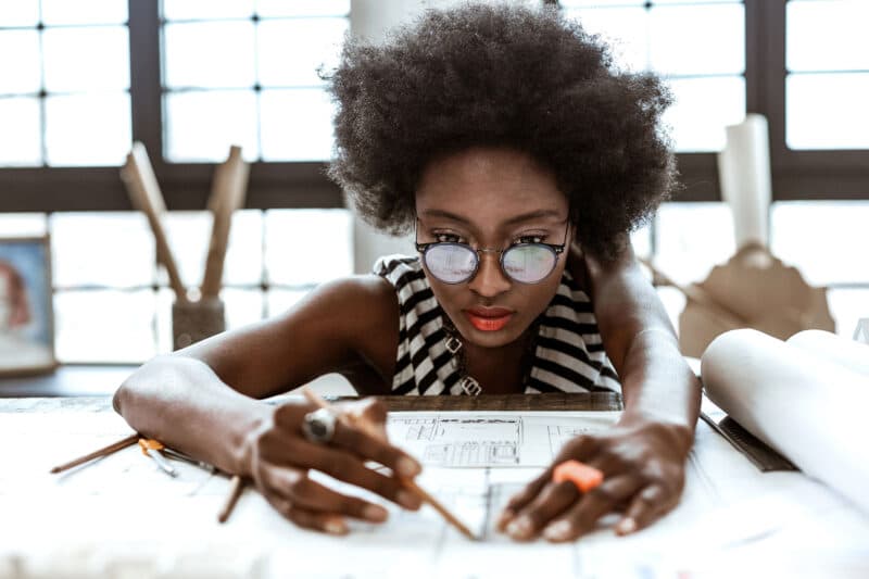 woman in glasses writing on paper with pencil
