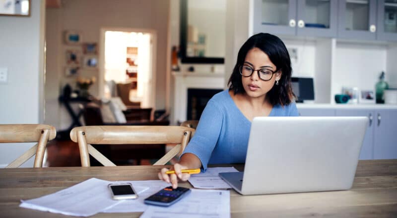 woman at table using phone and laptop