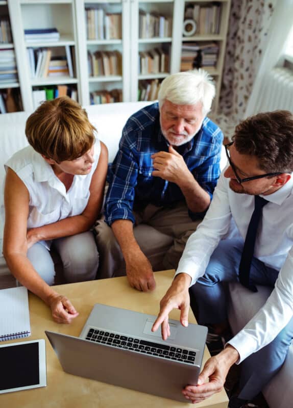 three people looking at laptop on coffee table