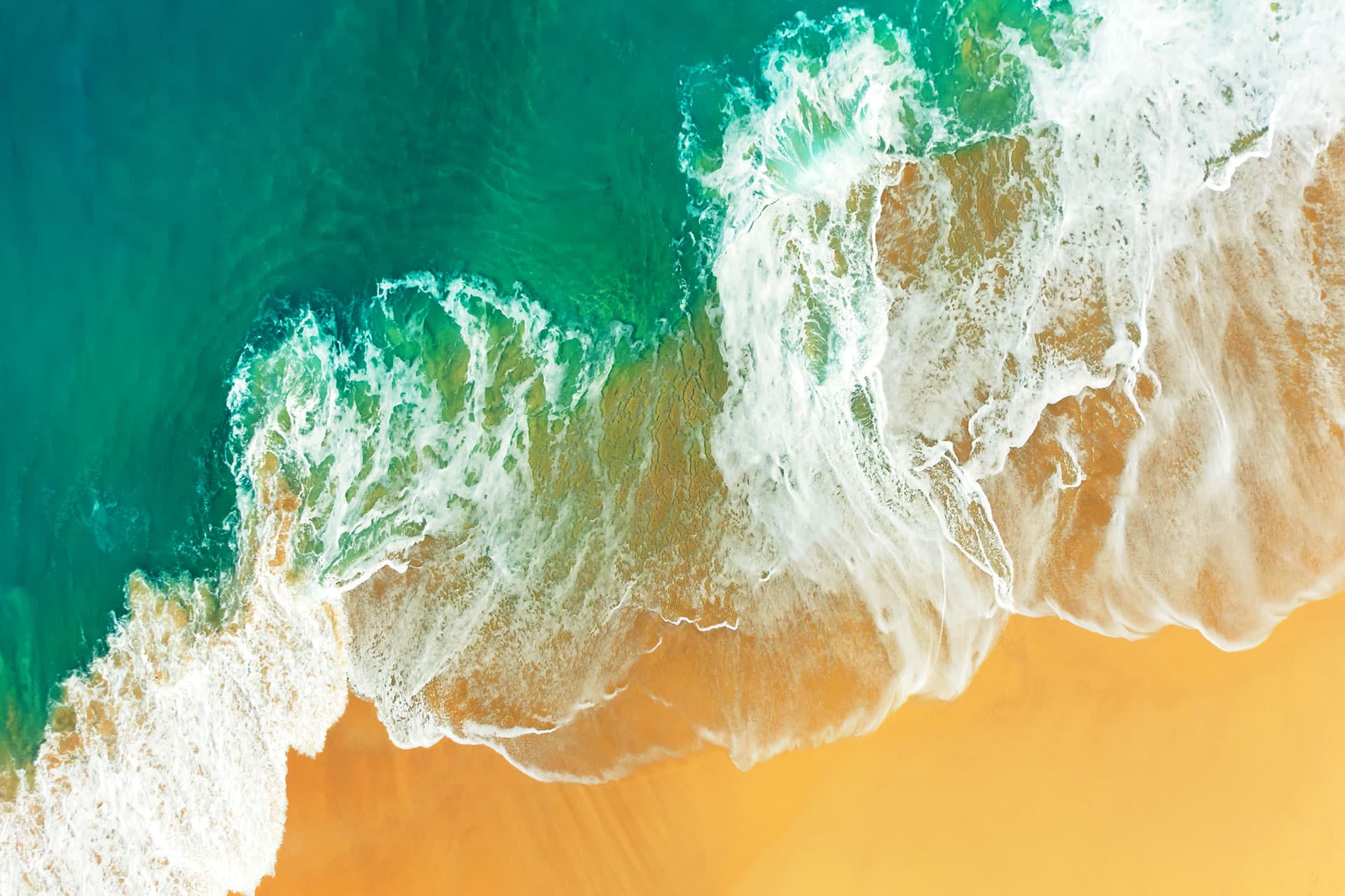 aerial view of turquois waves breaking on orange beach