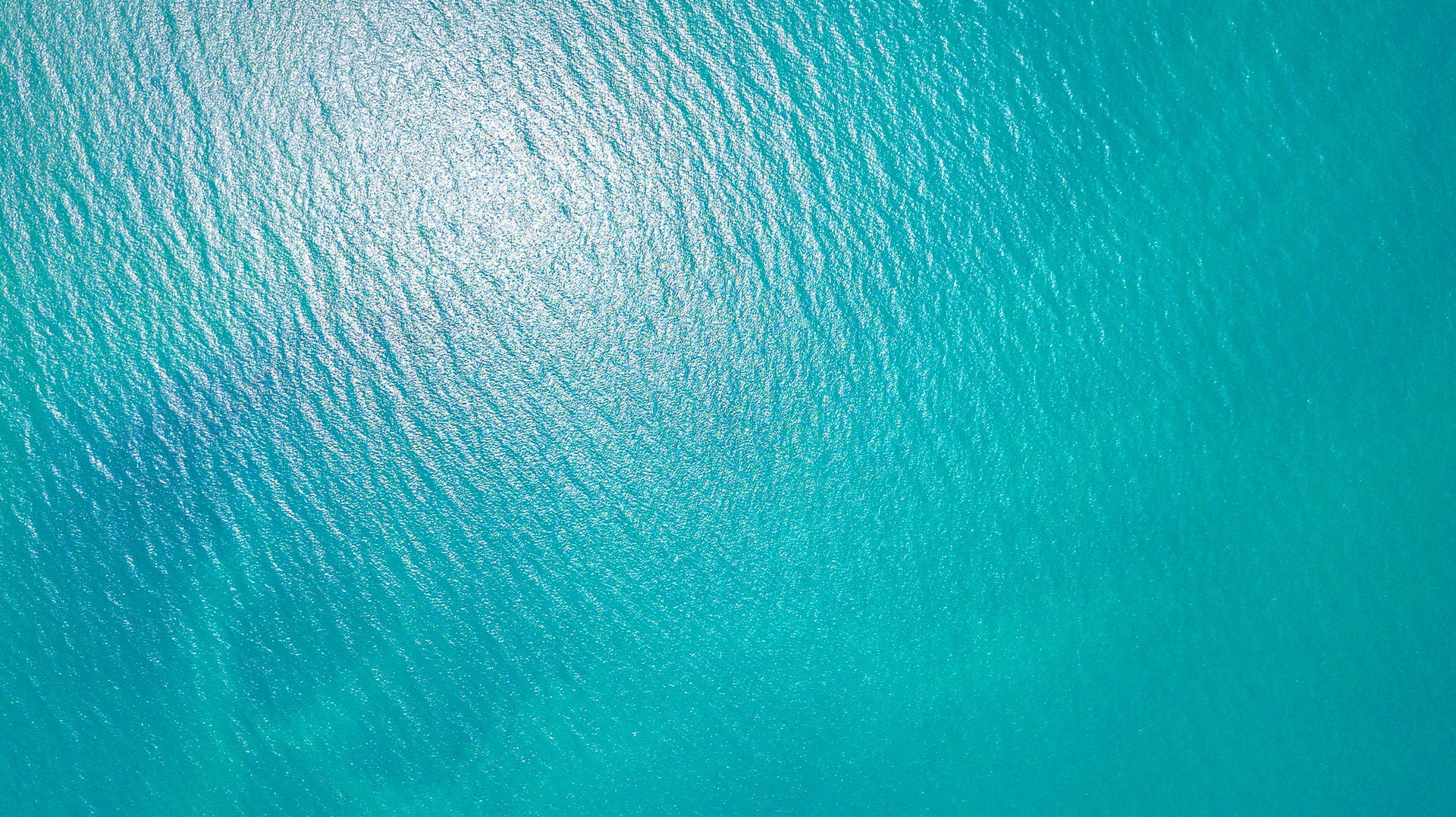 aerial view of bright turquoise ocean ripples